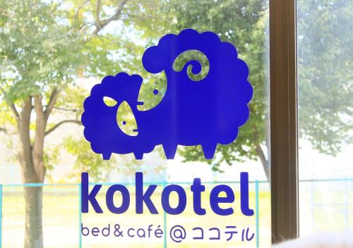 a sign with a blue sheep on a window at Kokotel Hakodate in Hakodate