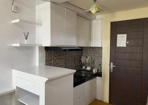 uma cozinha com armários brancos e um lavatório preto em Apartemen Malioboro city by Ameliarooms em Yogyakarta