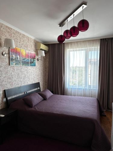 a bedroom with a bed with purple sheets and a window at Apartment on Agrba in Pizunda