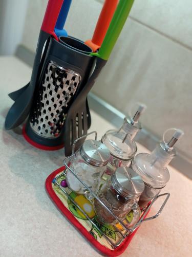 a container with a bunch of utensils next to a blender at Joseph 2 Stylish flat with open views, just 4km from the airport or beach in Siġġiewi