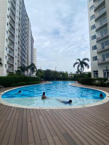 two people swimming in a large swimming pool with buildings at Luxury Two Bedroom with Balcony in SOUTH RESIDENCE of Las Pinas in Manila