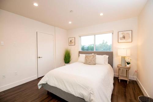 a white bedroom with a large bed and a window at Luxury 2Bed/2Bath Apt in West Hollywood w/ Rooftop in Los Angeles
