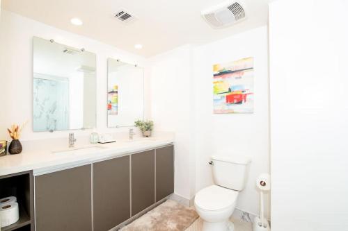 a bathroom with a toilet and two sinks and a mirror at Luxury 2Bed/2Bath Apt in West Hollywood w/ Rooftop in Los Angeles