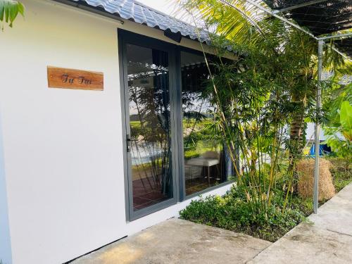 a white house with a window with a sign on it at LUA Farmstay in Ba Ria