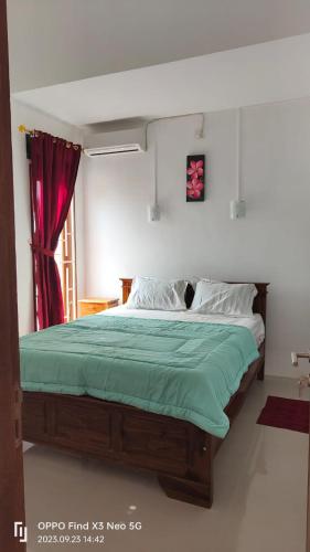 a bedroom with a large bed with a green blanket at Jatisela homestay in Midang