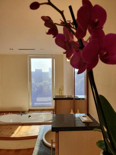 La salle de bains est pourvue d'une baignoire et d'un vase avec des fleurs violettes. dans l'établissement Huize La Passion vacationhouse 10 min walk from the sea, à Middelkerke