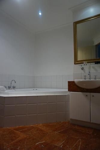 a bathroom with a tub and a sink and a mirror at Acacia Terraces in Echuca