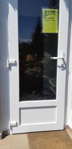 a white door with a window with a sign on it at Apartman YVET in Sučany
