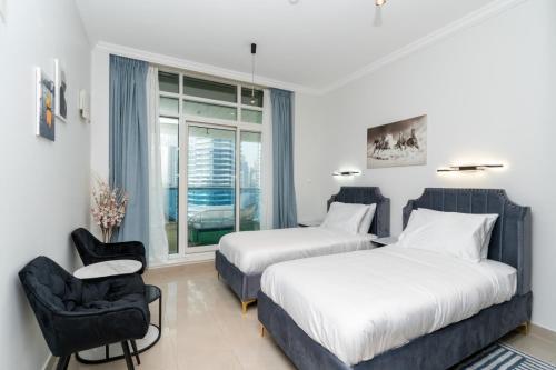 1 dormitorio con 2 camas, silla y ventana en Marina Yacht Club Views - 3BR Modern Furnished en Dubái