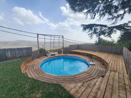 a small swimming pool in a backyard with a wooden deck at Biktot Ba Arafel in Nimrod