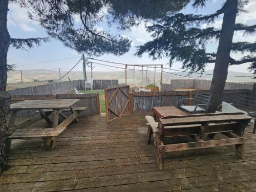 a wooden deck with two picnic tables and a fence at Biktot Ba Arafel in Nimrod