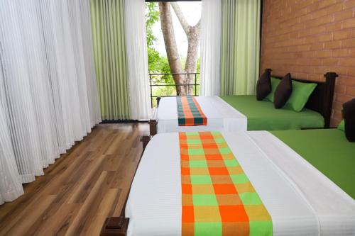 two beds in a room with green and orange at Life of Leisure Wilpattu in Pahala Maragahawewa