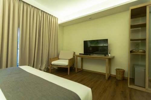 a hotel room with a bed and a tv and a chair at Isla Amara Resort in El Nido