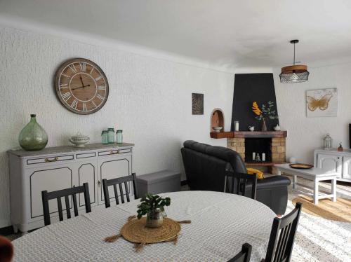 - un salon avec une table et une horloge murale dans l'établissement Villa des petites Chaumes, à Avallon