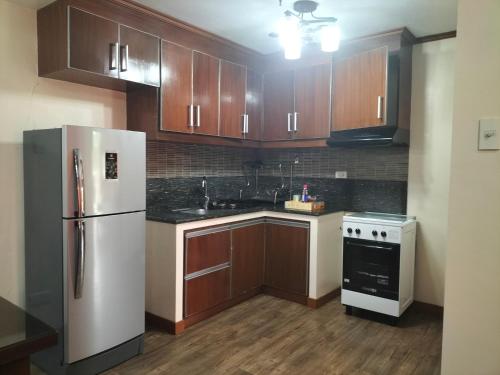 a kitchen with a white refrigerator and wooden cabinets at havens comfy apartments at Bonbel Condominium in Baguio