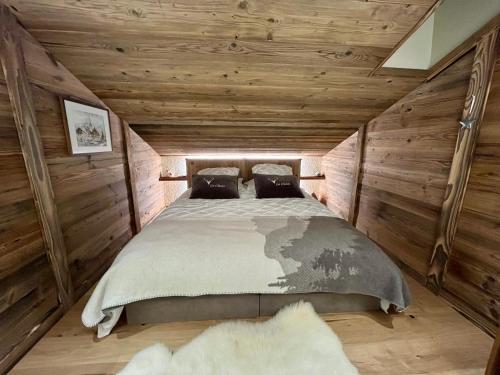 a bedroom with wooden walls and a large bed at Appartement cosy vue montagne in La Clusaz