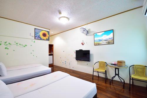 um quarto com duas camas e uma televisão e uma mesa em Chin Shan B&B em Guanshan
