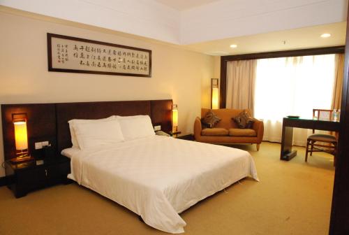 a bedroom with a large white bed and a chair at 东莞君兰酒店 Grand land hotel in Dongguan