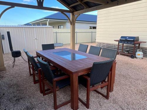 einem Holztisch mit Stühlen und einem Grill im Hinterhof in der Unterkunft Copper Shores Holiday House in Wallaroo