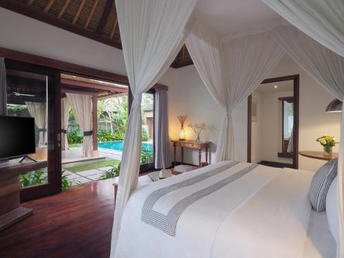 a bedroom with a large white bed and a television at The One Boutique Villa in Seminyak