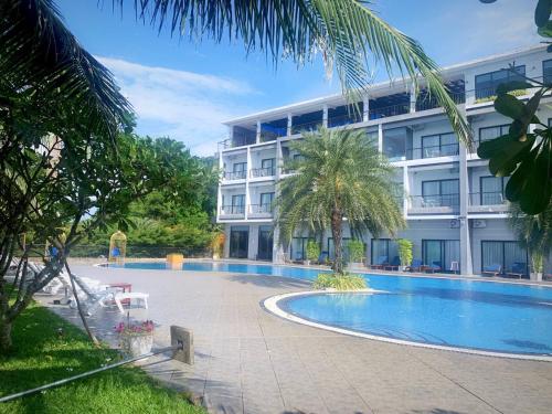 a hotel with a swimming pool in front of a building at KEP BAY HOTEL & RESORT in Kep