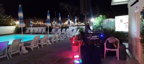 un gruppo di sedie e una piscina di notte di Hotel Nuovo Belvedere a Rimini