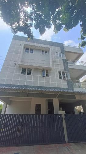 a large white house with a fence in front of it at Shantham Service Apartments, Indumanagar, Coimbatore in Coimbatore