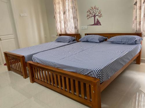 two beds with blue and white striped sheets in a bedroom at Shantham Service Apartments, Indumanagar, Coimbatore in Coimbatore