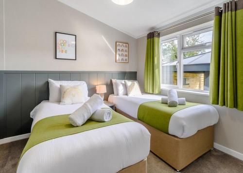 Raywell Hall Country Lodges في Skidby: سريرين في غرفة مع ستائر خضراء