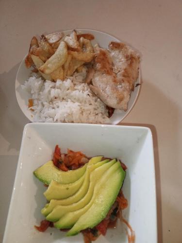 dois pratos brancos de alimentos com arroz e abacate em Como en Casa em Caracas