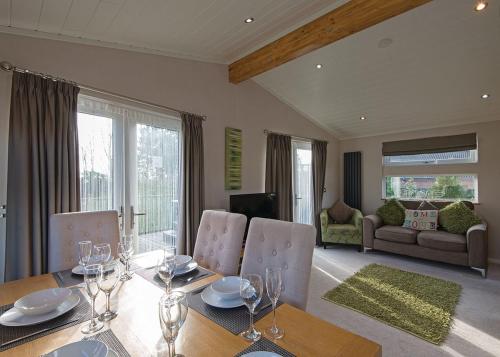 a dining room with a table and chairs and a living room at Raywell Hall Country Lodges in Skidby