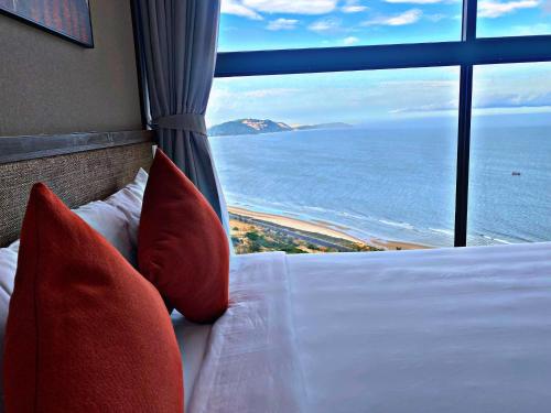 a bedroom with a bed with a view of the ocean at Apec MANDALA CHAM BAY MUI NE SPA RESORT AND CONDOTEL in Ấp Thiẹn Ái