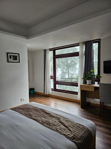 a bedroom with a large bed and a large window at Shanol Residency in Gangtok