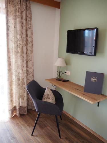 a room with a chair and a television on a wall at Hotel Garni Kern in Halfing