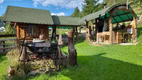 a log cabin with an old tractor in front of it at Casa Rustik Bucovina in Fundu Moldovei