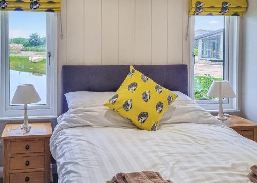 a bedroom with a bed with two lamps and two windows at Lakeside Luxury Lodges in Thorney