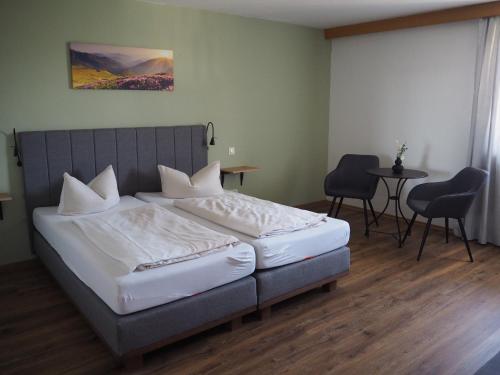 een slaapkamer met een bed en een tafel en stoelen bij Hotel Garni Kern in Halfing