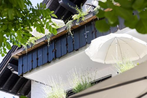 a white umbrella sitting on a balcony with a blue shutter at Pension Auszeit in Langenargen