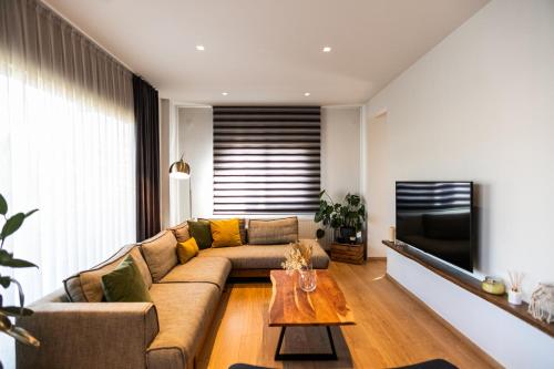 a living room with a couch and a television at AEGLI Central Luxury Apartment in Alexandroupoli