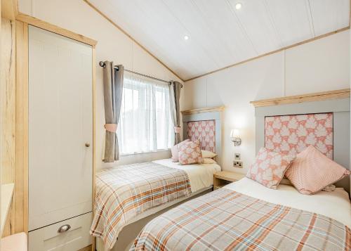 a small bedroom with two beds and a window at Brighouse Bay Holiday Park in Kirkcudbright