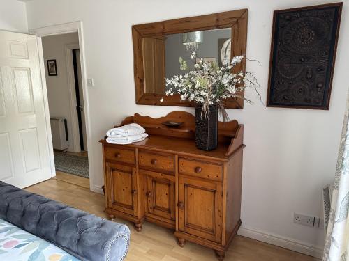 a dresser with a mirror and a vase of flowers on it at Coleraine Riverside apartment in Coleraine