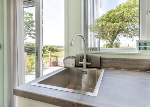 uma cozinha com um lavatório de aço inoxidável em frente a uma janela em Calvesland Hideaway em Manorbier