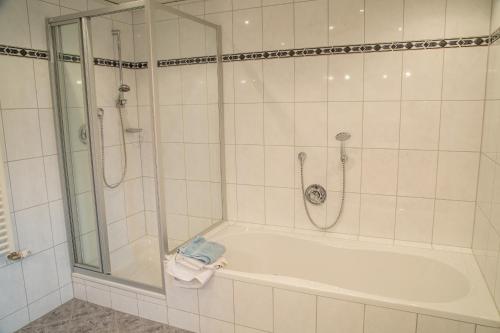 y baño blanco con ducha y bañera. en Maurerhof en Ruhpolding