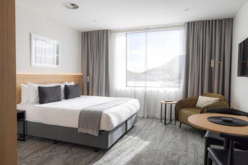 a hotel room with a bed and a desk and a chair at Quest Mt Maunganui in Mount Maunganui