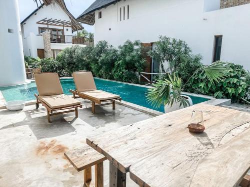 Villa Upendo with pool, Zanzibar في بينجوي: فناء مع كرسيين وطاولة خشبية