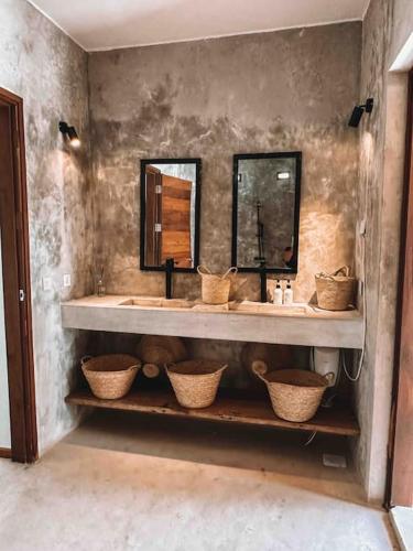 a bathroom with two sinks and two mirrors and baskets at Villa Upendo with pool, Zanzibar in Pingwe
