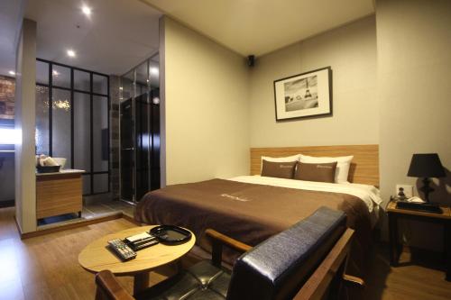 um quarto de hotel com uma cama e uma mesa em The May Hotel em Busan