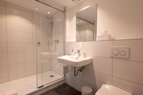 a bathroom with a sink and a shower and a toilet at Hotel Fischerhaus in Düsseldorf