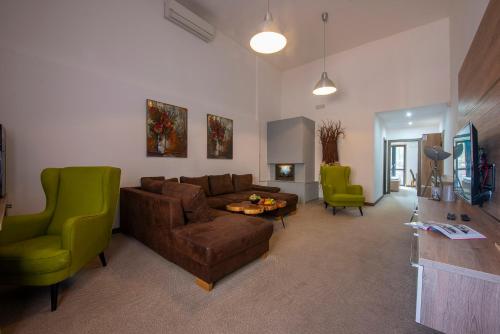 a living room with a brown couch and green chairs at Wellness Hotel Vinnay in Vinné