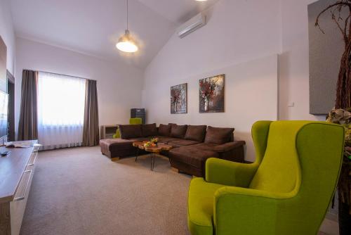 a living room with a couch and a green chair at Wellness Hotel Vinnay in Vinné